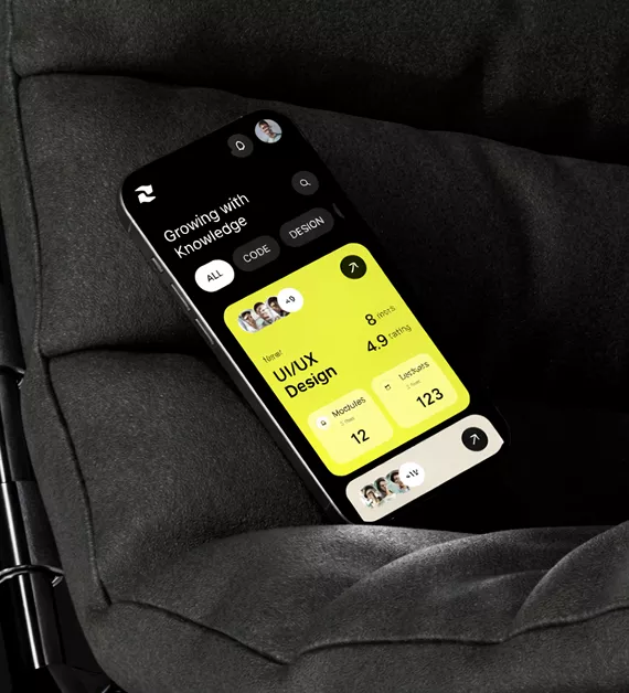 Smartphone on dark fabric showing UI/UX design learning app with bright yellow interface displaying course modules, user stats, and progress metrics
